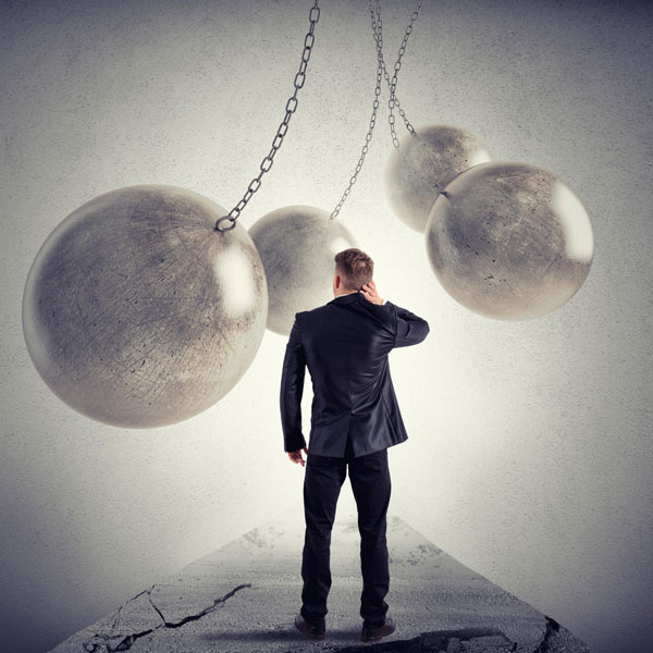 Man walking through giant wrecking balls, signifying stepping outside of your comfort zone