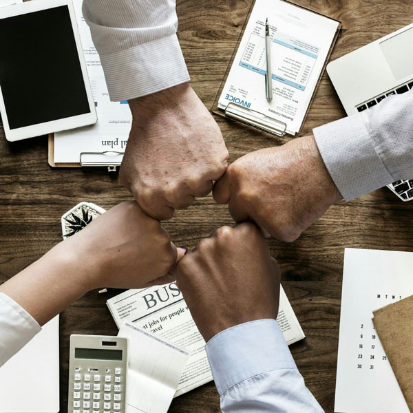 4 people's hands in fists coming together, signifying teamwork and delegation